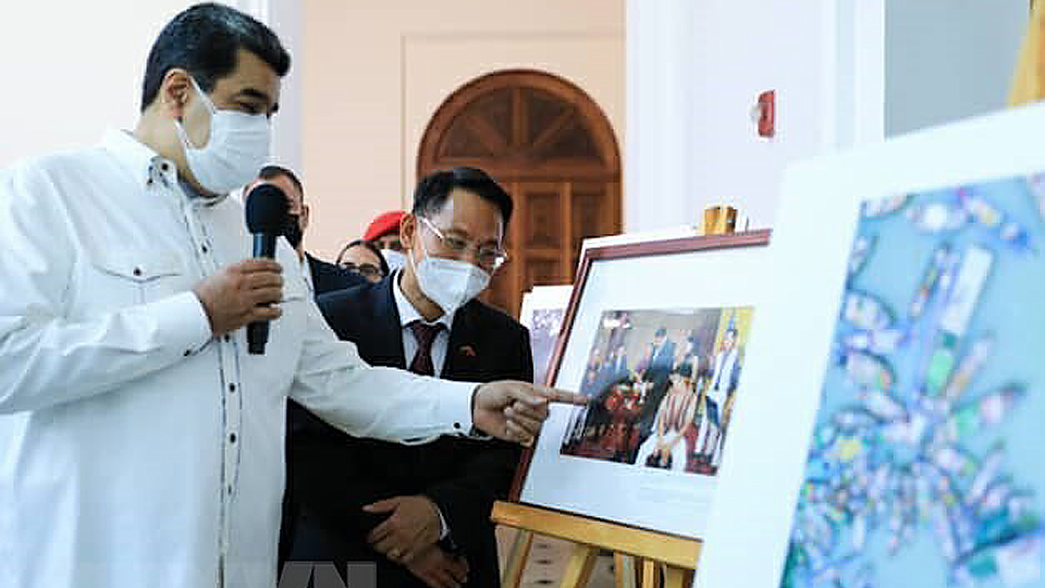 Tổng thống Maduro trao đổi cùng Đại sứ Việt Nam tại Venezuela Lê Viết Duyên về những bức ảnh của Việt Nam trưng bày tại Hội chợ. Ảnh: TTXVN