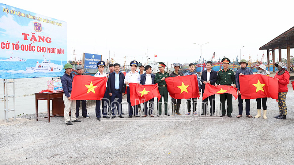 Các đồng chí lãnh đạo UBND tỉnh và Bộ Tư lệnh Cảnh sát biển Việt Nam tặng quà và cờ Tổ quốc cho ngư dân đang neo đậu tại Cảng cá Ninh Cơ, thị trấn Thịnh Long (Hải Hậu).