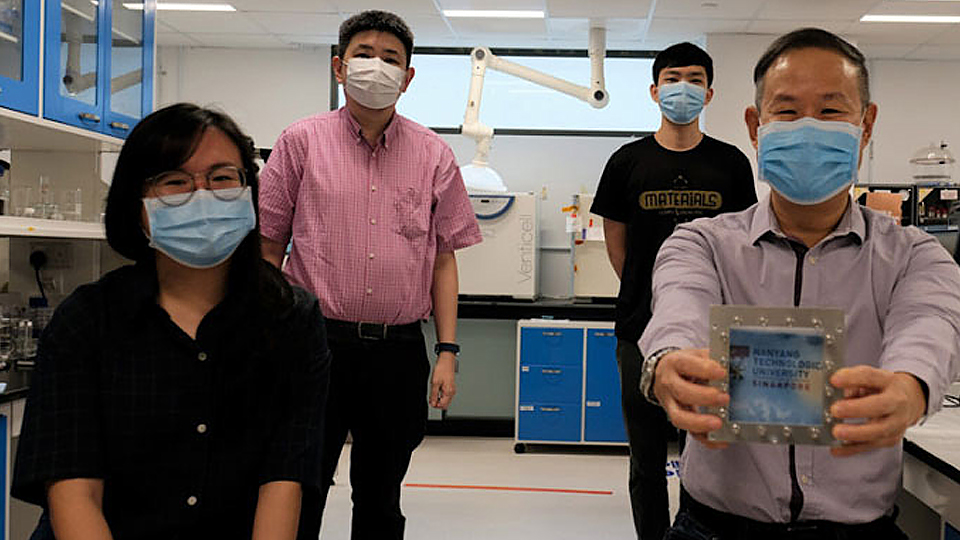 Nhóm nghiên cứu tại Đại học Công nghệ Nanyang với mẫu kính cửa sổ kết hợp vật liệu mới. (Ảnh: NTU Singapore).