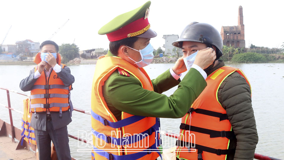 Công an huyện Trực Ninh hướng dẫn người đi đò thực hiện nghiêm việc đeo khẩu trang nơi công cộng phòng, chống dịch COVID-19.