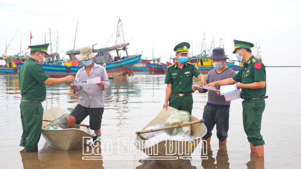 Cán bộ, chiến sĩ Đồn Biên phòng Quất Lâm (Giao Thủy) phát tờ gấp tuyên truyền về chủ quyền biên giới biển cho ngư dân.