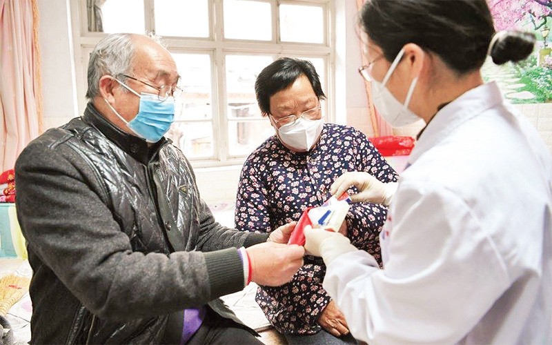 Nhân viên y tế hỗ trợ người cao tuổi ở tỉnh Hồ Bắc, Trung Quốc. (Ảnh TÂN HOA XÃ)