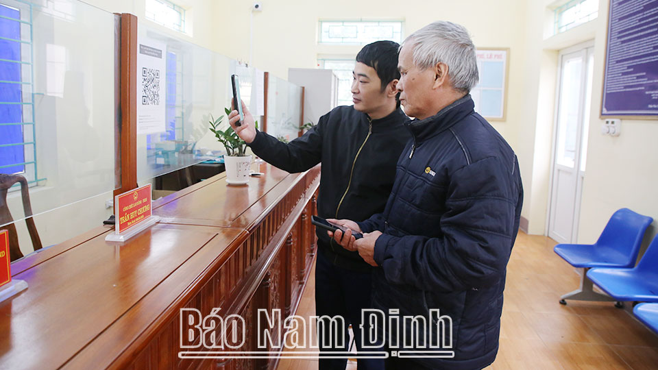 Cán bộ xã Kim Thái (Vụ Bản) hướng dẫn người dân ứng dụng thanh toán điện tử để nộp phí dịch vụ công.