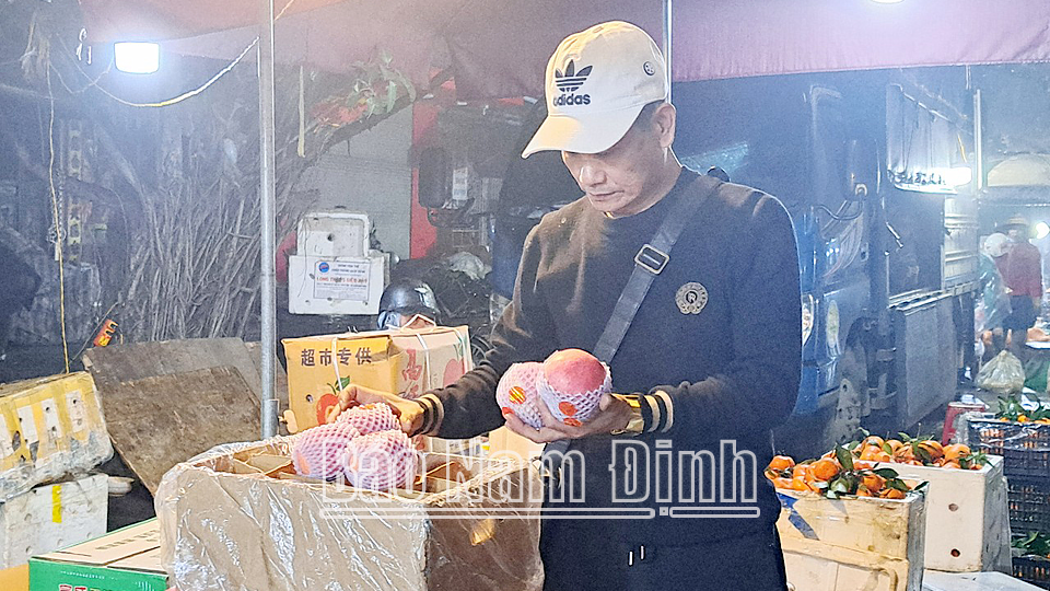 Khách hàng chọn mua hoa quả tại chợ đêm trên đường Trần Hưng Đạo (thành phố Nam Định).
