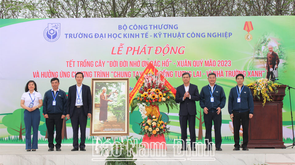 Đồng chí Trần Lê Đoài, TUV, Phó Chủ tịch UBND tỉnh tặng Trường Đại học Kinh tế - Kỹ thuật Công nghiệp lẵng hoa tươi thắm và bức tranh Bác Hồ chăm sóc cây trong vườn cây của Bác.