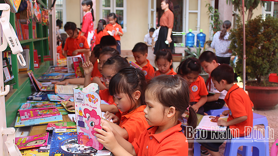 Học sinh Trường Tiểu học Lộc Hạ (thành phố Nam Định) đọc sách tại xe ô tô thư viện lưu động đa phương tiện.
