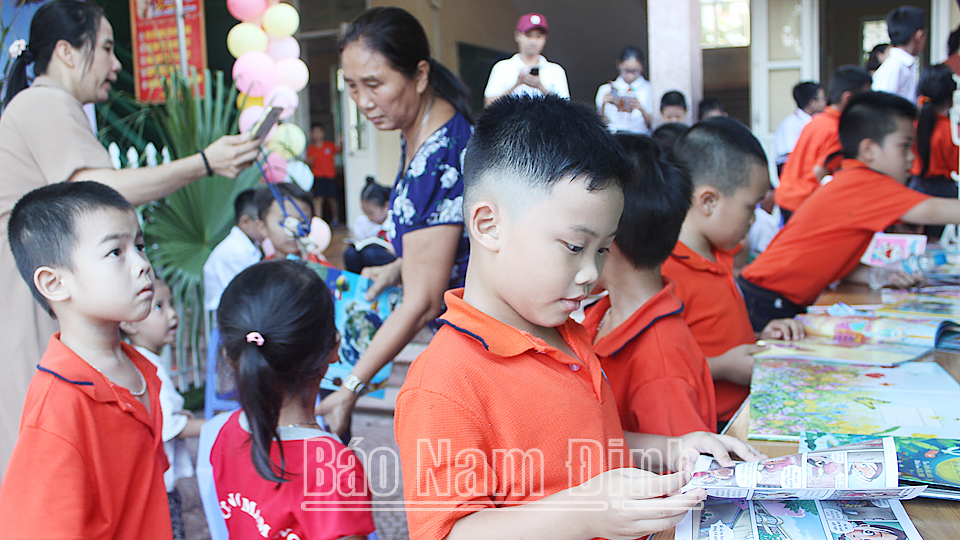 Học sinh Trường Tiểu học Lộc Hạ (thành phố Nam Định) đọc sách tại xe ô tô thư viện lưu động đa phương tiện của Thư viện tỉnh.