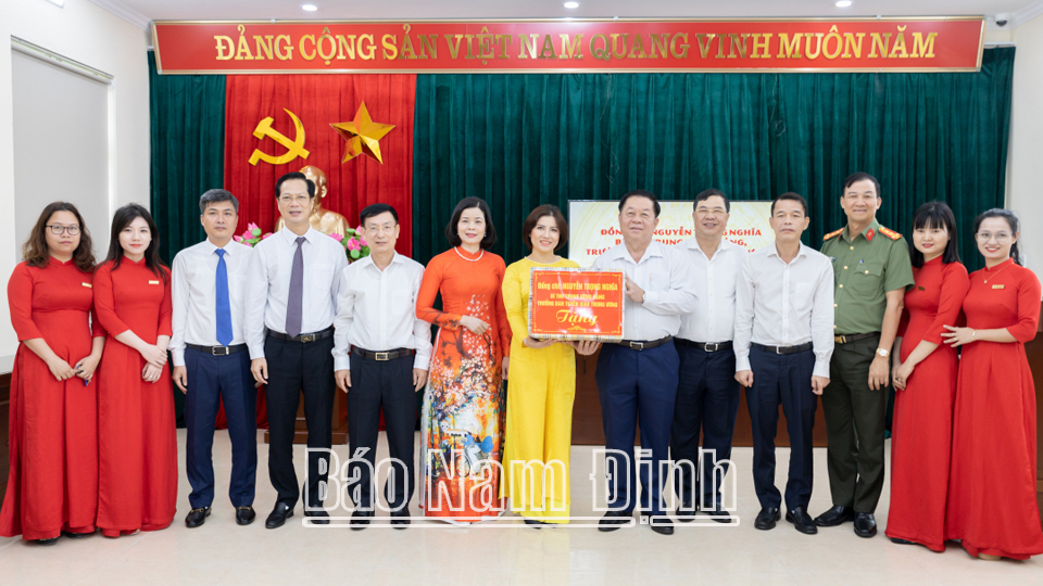Đồng chí Trưởng Ban Tuyên giáo Trung ương Nguyễn Trọng Nghĩa tặng quà cô và trò trường Tiểu học Nguyễn Tất Thành (thành phố Nam Định). 