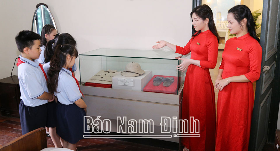 Cô và trò Trường Tiểu học Nguyễn Tất Thành (thành phố Nam Định) tìm hiểu các hiện vật về Bác Hồ được trưng bày tại Nhà truyền thống ngành Dệt May Việt Nam.