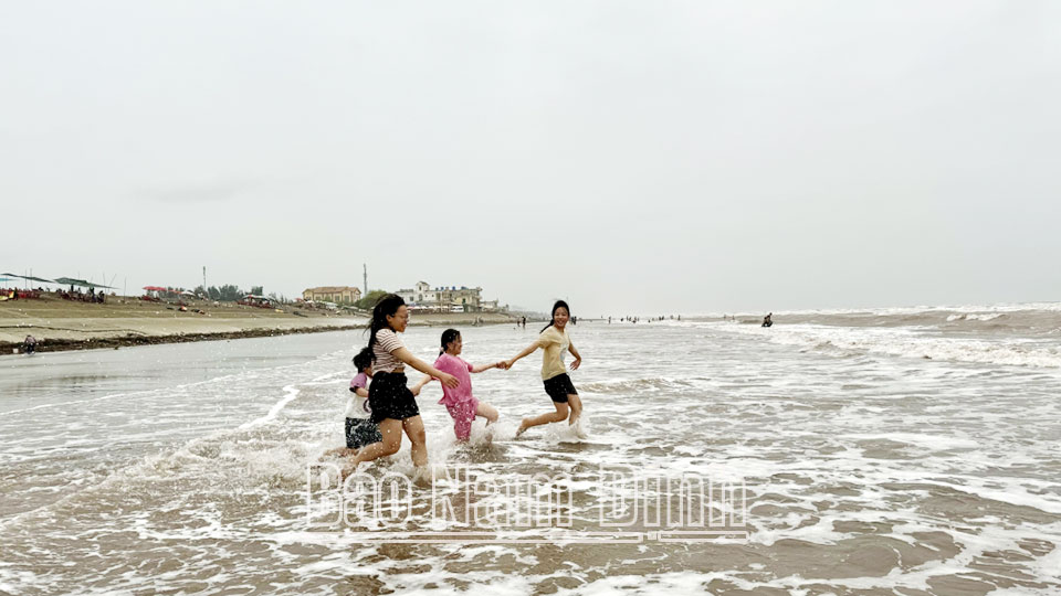 Du khách thỏa thích nô đùa cùng sóng biển tại bãi biển thị trấn Thịnh Long.