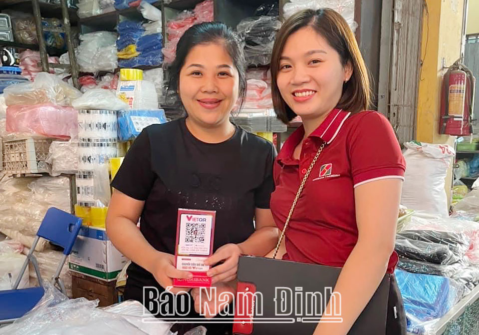 Cán bộ Agribank Chi nhánh tỉnh Nam Định trao thiết bị, phụ kiện phục vụ thanh toán bằng mã VietQR cho tiểu thương ở chợ Rồng (thành phố Nam Định).ĐT2