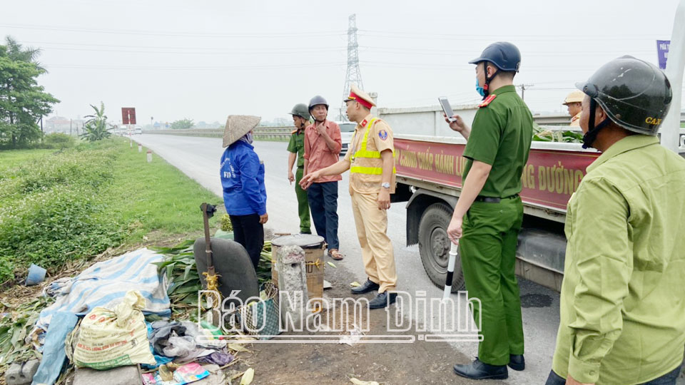 Các lực lượng chức năng huyện Vụ Bản nhắc nhở người dân không buôn bán bên lề đường giao thông.