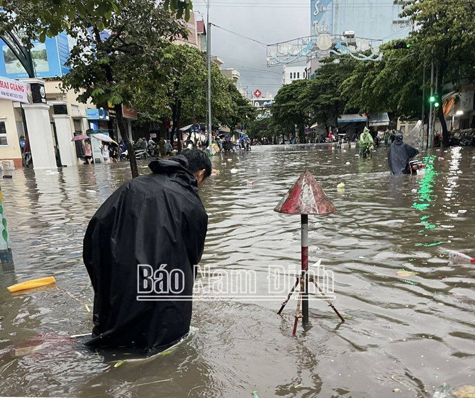 Cán bộ Công ty Cổ phần Công trình đô thị Nam Định trực và cắm biển cảnh báo nguy hiểm do ngập tại đường Trần Hưng Đạo.