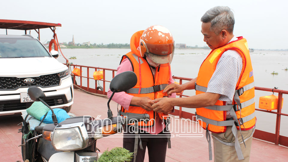 Hỗ trợ, hướng dẫn hành khách mặc áo phao khi tham gia giao thông đường thủy nội địa tại bến đò Cau, xã Nghĩa Sơn.
