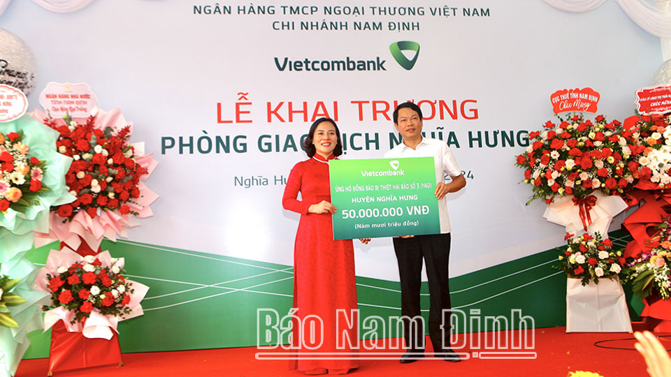 Bà Đoàn Thị Hồng Nga, Giám đốc Vietcombank Nam Định trao tặng tiền hỗ trợ người dân bị ảnh hưởng bởi bão số 3 trên địa bàn huyện Nghĩa Hưng. Dt2