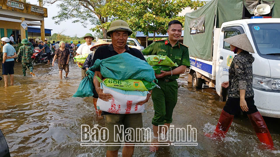 Công an xã Phương Định (Trực Ninh) giúp người dân nhận hàng cứu trợ khi trở về nhà sau lũ. (ĐT 6)