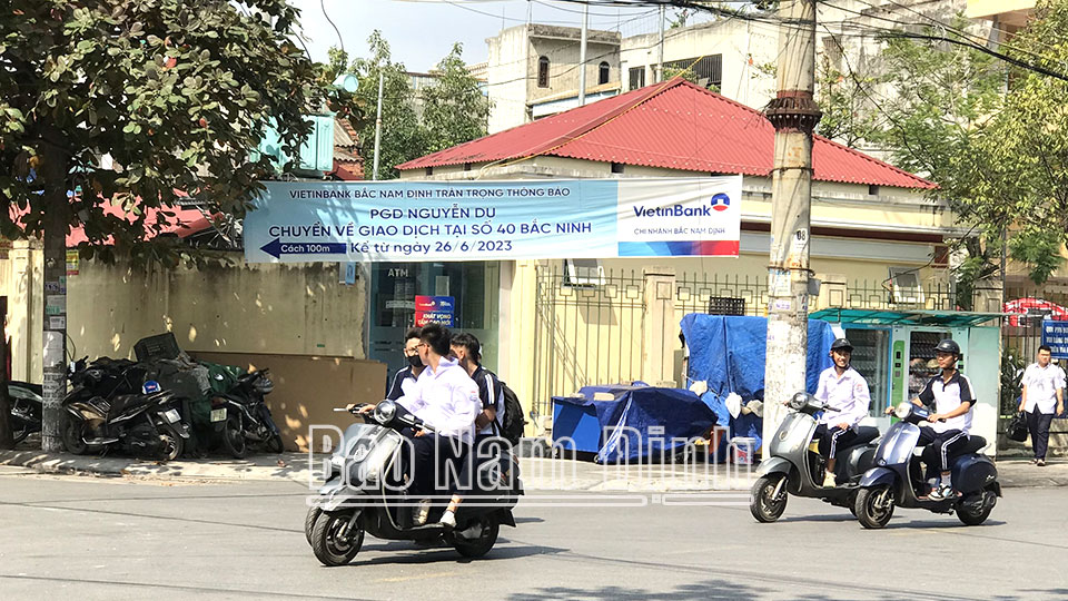 Học sinh đi xe máy điện không đội mũ bảo hiểm trên đường Nguyễn Du (thành phố Nam Định).