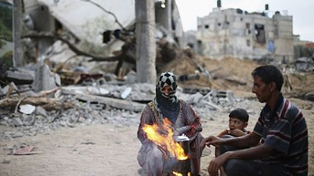 Người dân Palestine bên những đống đổ nát ở dải Gaza. (Ảnh: Reuters).