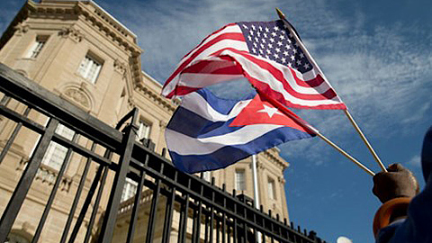 Một người dân mang lá cờ Mỹ và cờ Cuba đến ăn mừng trước Đại sứ quán mới của Cuba tại Oa-sinh-tơn ngày 20-7. Ảnh: AP