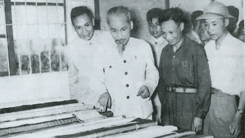 Chủ tịch Hồ Chí Minh và các đồng chí Trần Đăng Bái, Bí thư Đảng uỷ, đồng chí Võ Phong, Giám đốc Nhà máy Liên hợp dệt Nam Định, đang xem số vải “Vì miền Nam ruột thịt” do nhà máy sản xuất.