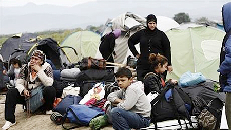 Người tị nạn và người di cư tại làng Idomeni đang đợi xe buýt đưa tới các trại tị nạn mới. (Ảnh: AP).