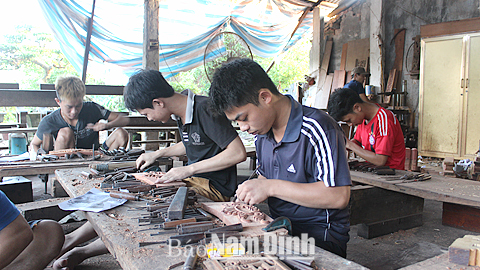 Lao động trẻ xã Hải Minh (Hải Hậu) chạm khắc các sản phẩm đồ gỗ.