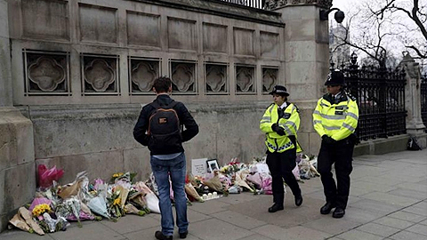 Các cảnh sát đi qua một địa điểm đặt hoa tưởng niệm các nạn nhân gần hiện trường vụ tấn công ngay sát Quốc hội Anh, tại London, ngày 24-3-2017. (Reuters)