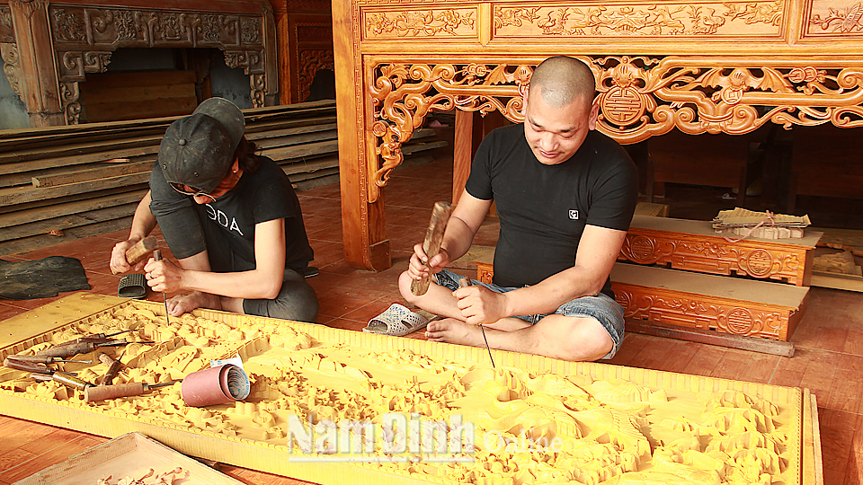 Anh Trịnh Văn Lợi (bên phải), xã Phương Định (Trực Ninh) đang điêu khắc tranh gỗ.