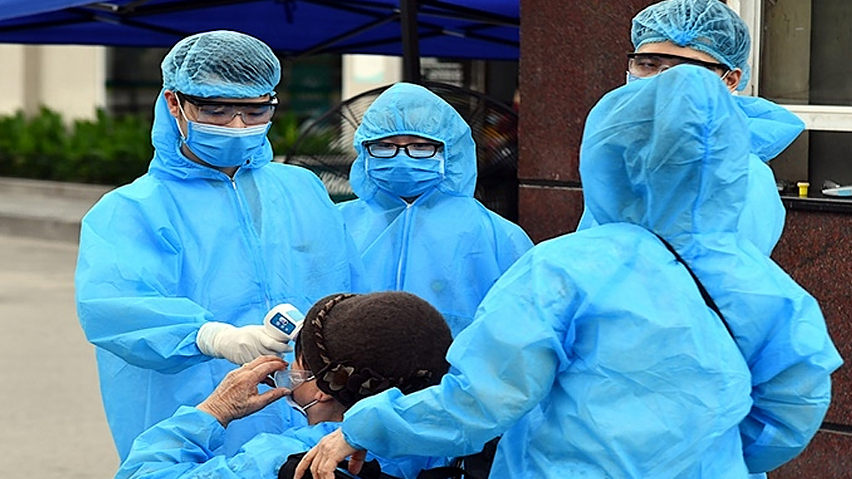 Một đội gồm bác sĩ và nhân viên y tế mặc đồ bảo hộ màu xanh làm nhiệm vụ đo thân nhiệt, yêu cầu sát khuẩn tay trước khi vào Bệnh viện Bạch Mai. 