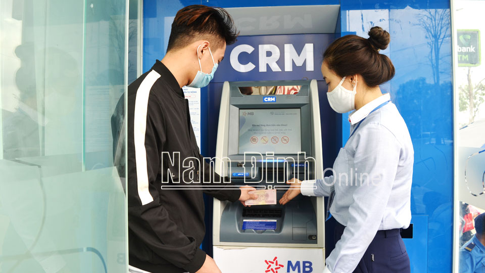 Cán bộ Ngân hàng TMCP Quân đội Chi nhánh Nam Định hướng dẫn người dân sử dụng máy CRM gửi/rút tiền tự động.