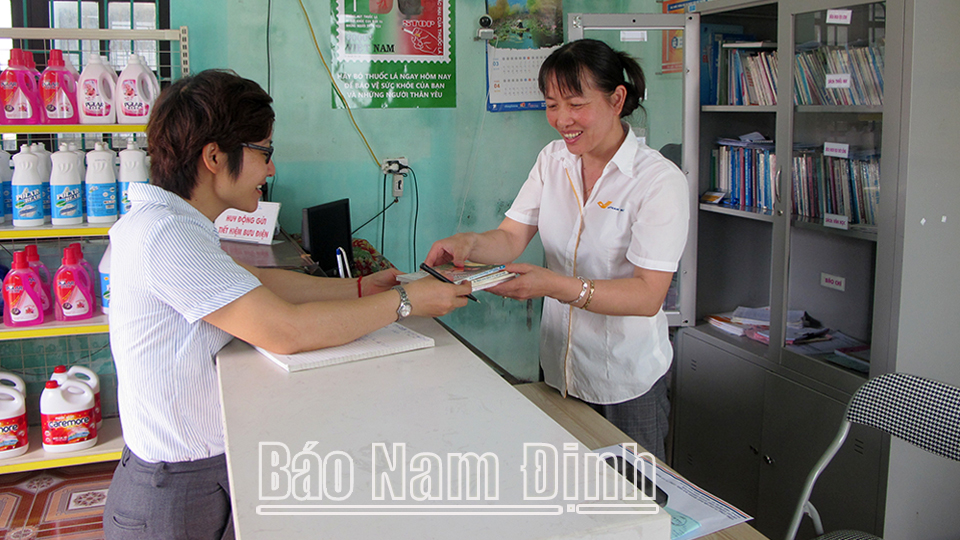 Nhân viên điểm bưu điện văn hóa xã Nghĩa Minh (Nghĩa Hưng) hướng dẫn người dân thực hiện thủ tục hành chính.