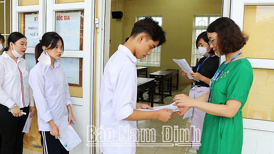 Cán bộ, giáo viên làm nhiệm vụ coi thi đọc số báo danh, kiểm tra thẻ dự thi của các thí sinh tại điểm thi Trường THPT Mỹ Lộc. Khánh Dũng